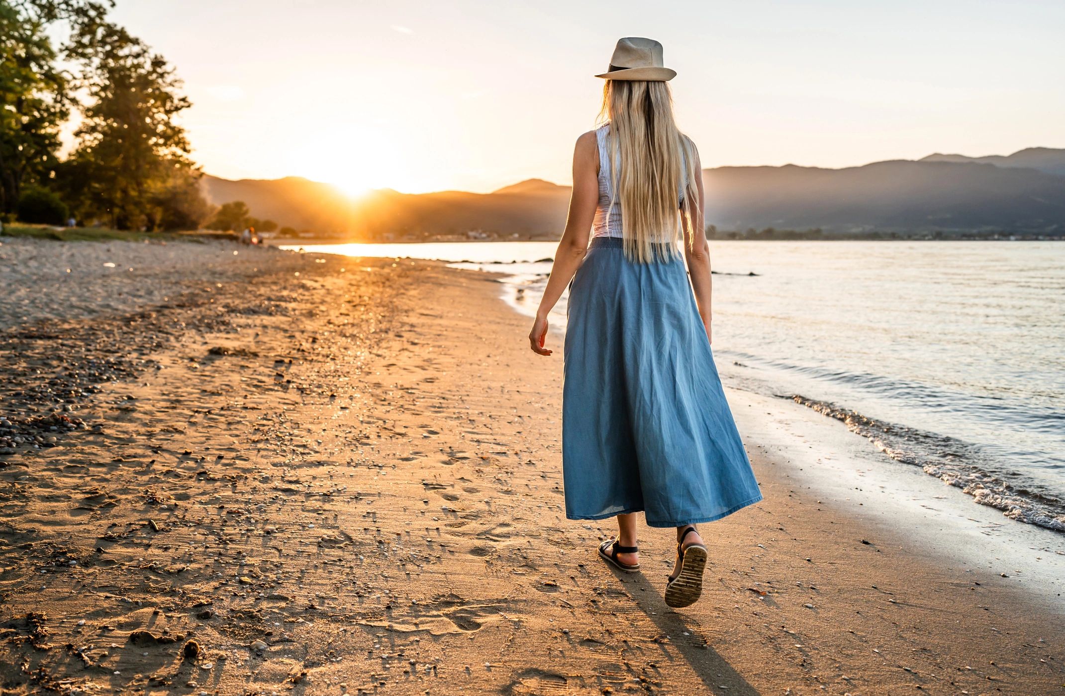 Woman walking peacefully along a beach at sunset