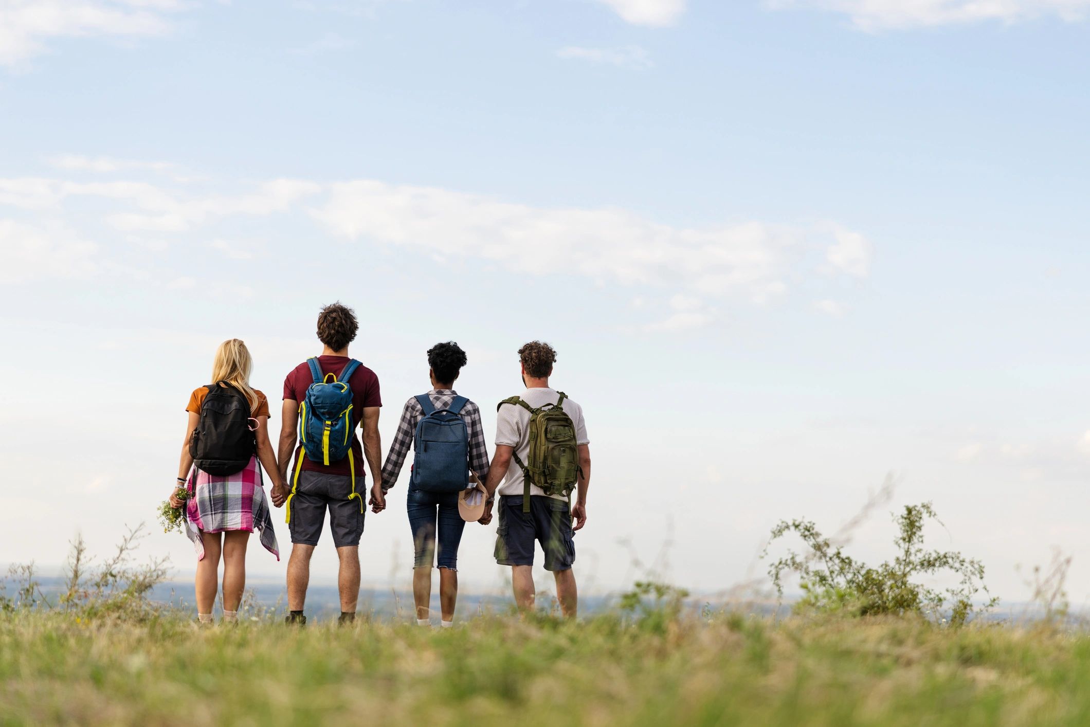 Friends standing together on a grassy hilltop