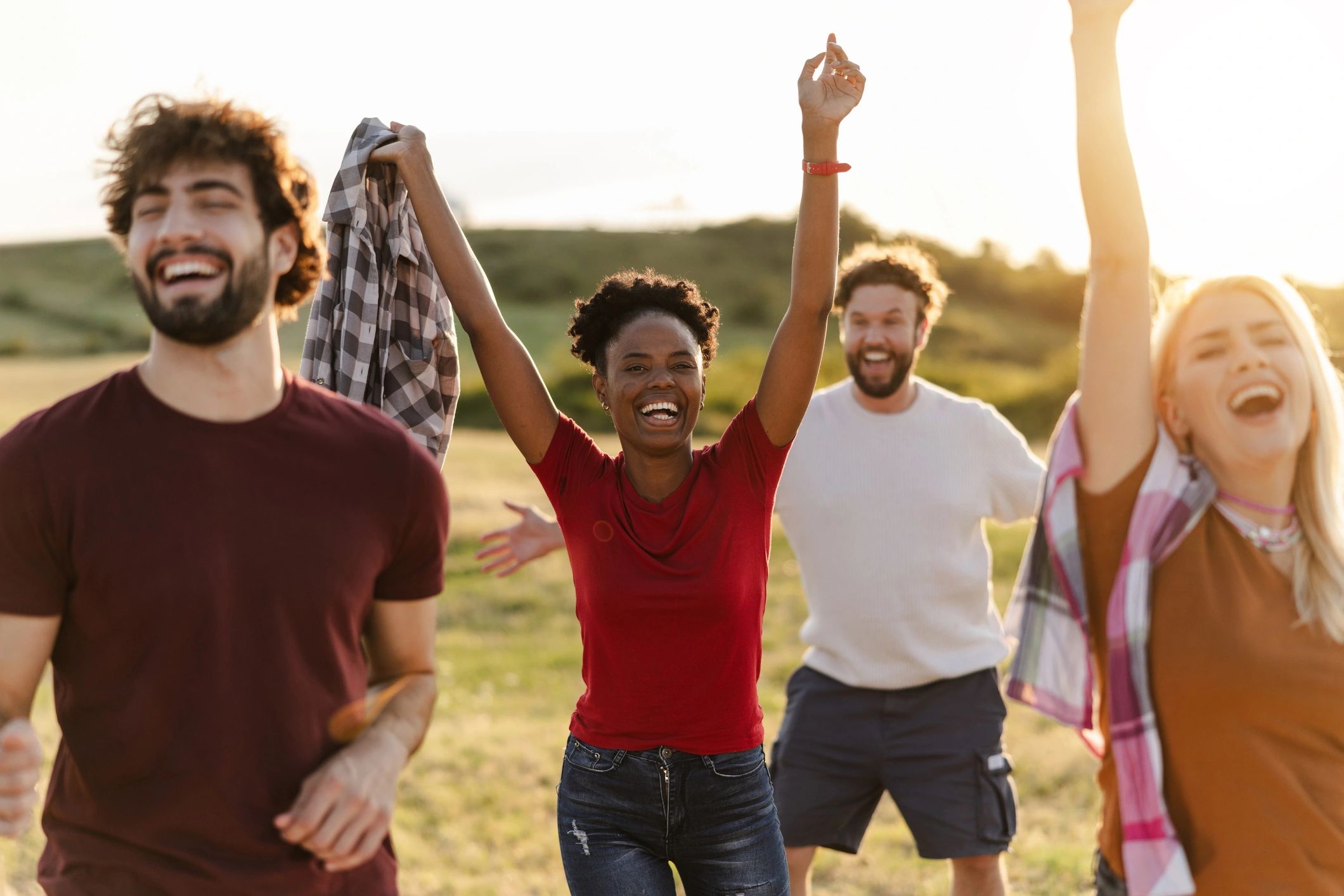 Group of joyful friends celebrating outdoors at sunset